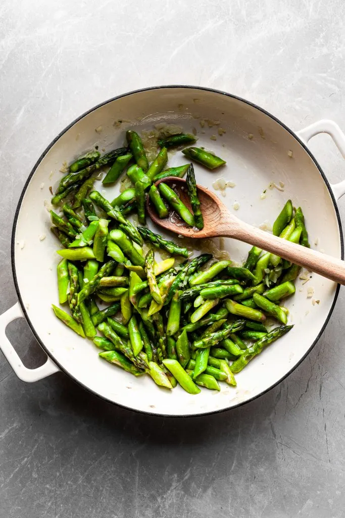 Flat lay of cooked asparagus in a white enamel skilllet