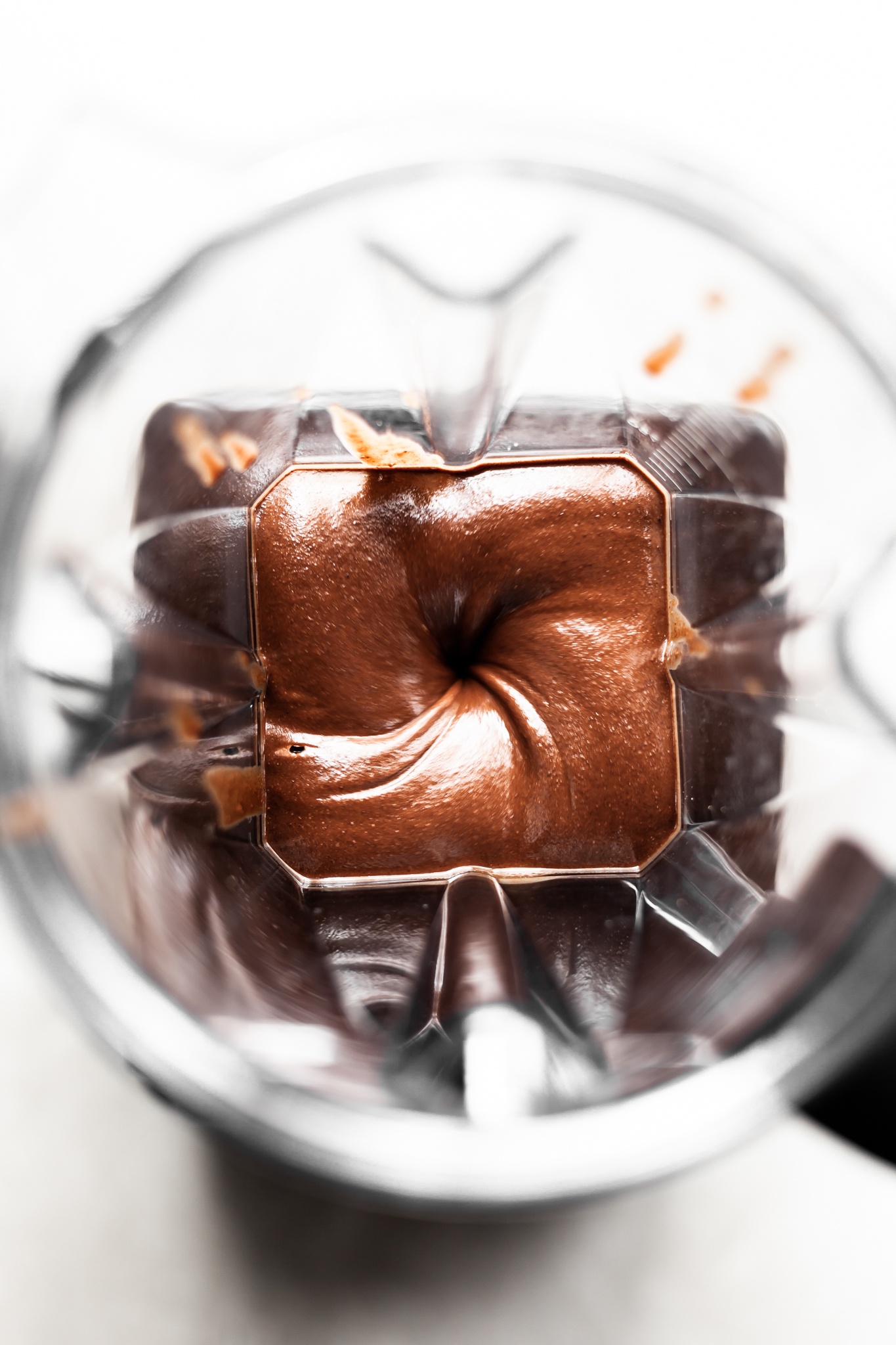 View looking down into a vitamix blender which is running, filled with chocolate hazelnut spread