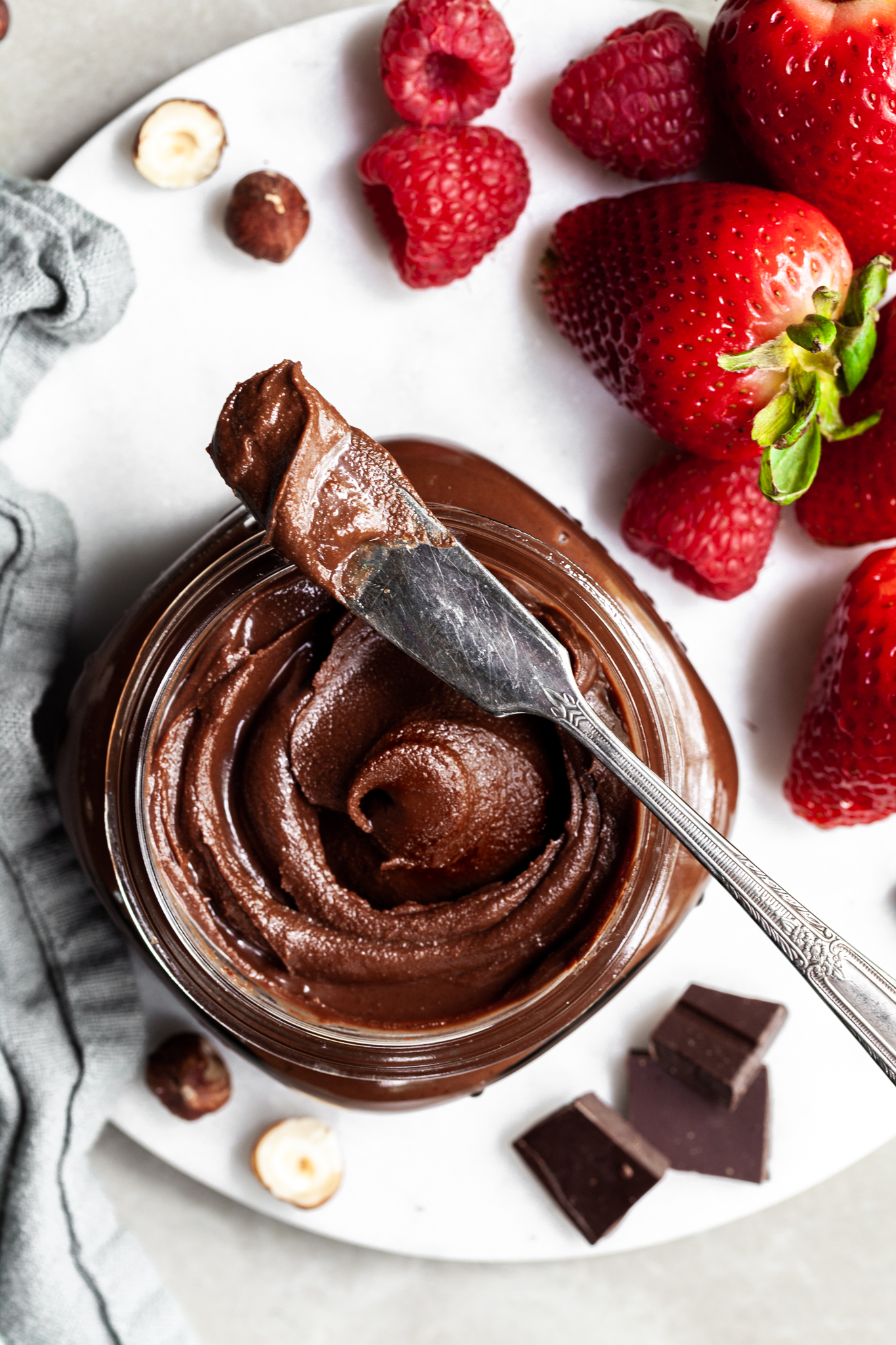 Looking down into a jar of vegan nutella surrounded by strawberries and raspberries