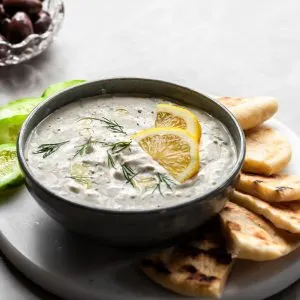 Vegan tzaztiki served in a blue bowl with Greek flatbread