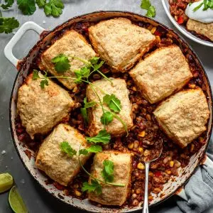 Chili pot pie in a white enamel skillet garnished with fresh cilantro leaves
