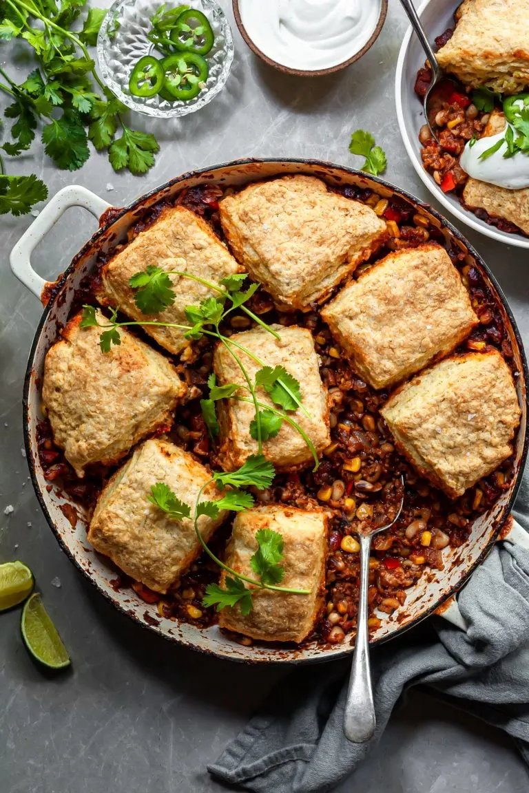 Chili pot pie in a white enamel skillet garnished with fresh cilantro leaves
