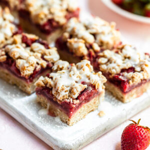 2 rows of strawberry oat bars on a narrow white cutting board