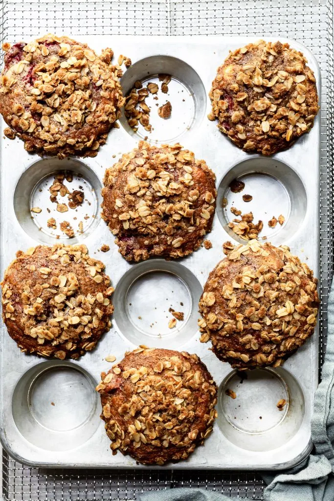 Fresh from the oven, a baking tray of strawberry muffins with domed caps covered in oatmeal streusel