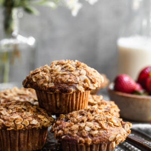Stack of muffins on an antique platter with a bowl of strawberries in the background