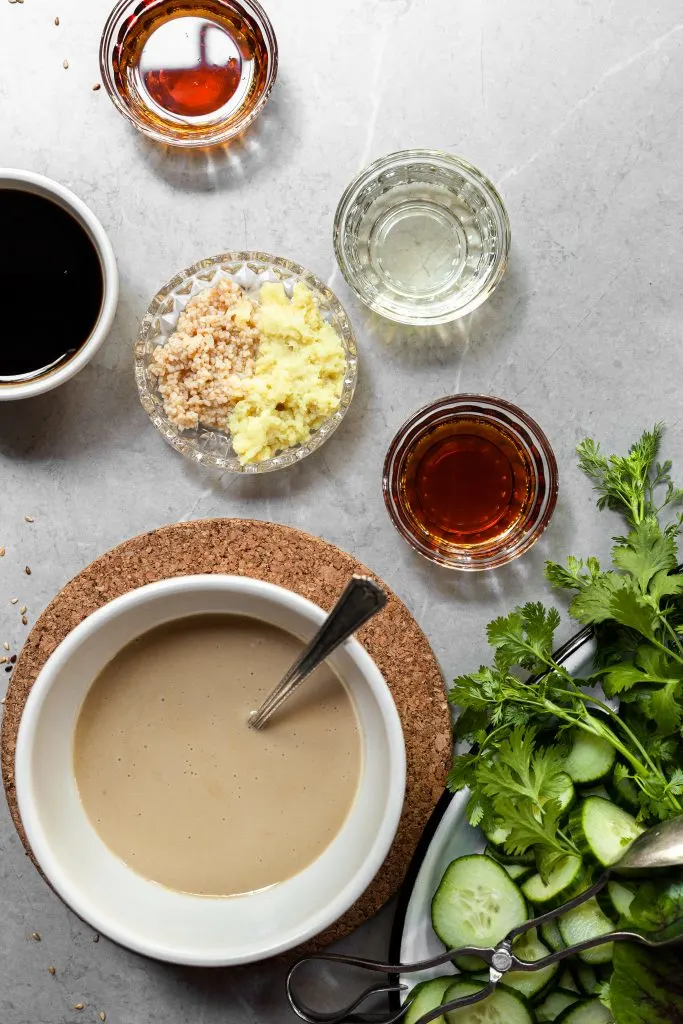Ingredients measured out in bowls for sesame ginger sauce beside a platter of fresh vegetables