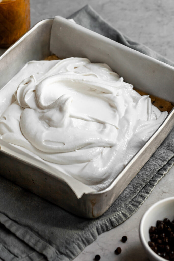 freshly churned vanilla ice sits piled in a square baking tray over a layer of cookie dough