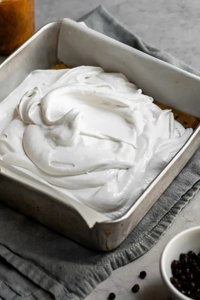 freshly churned vanilla ice sits piled in a square baking tray over a layer of cookie dough