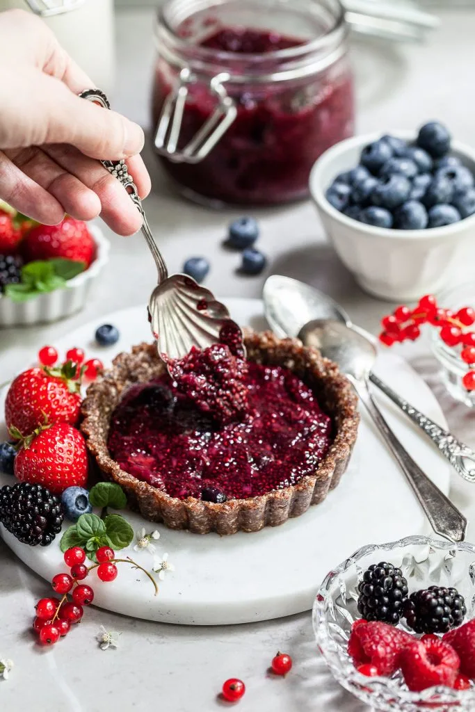 Berry Chia compote being spooned into a tart shell