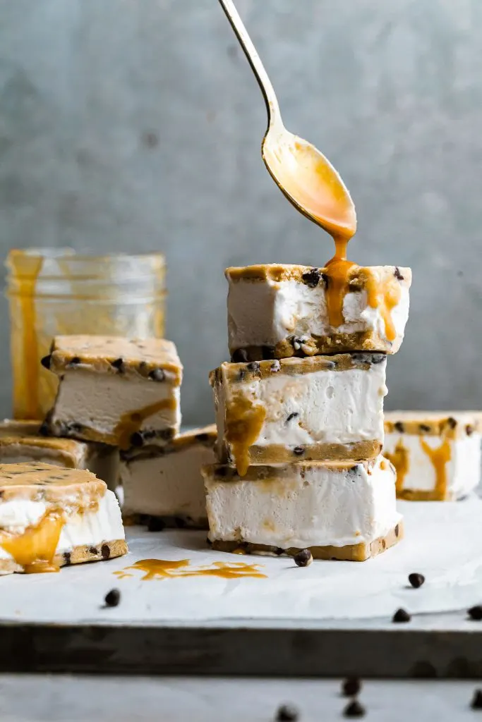 a spoon drips caramel onto a triple stack of cookie dough ice cream sandwiches 