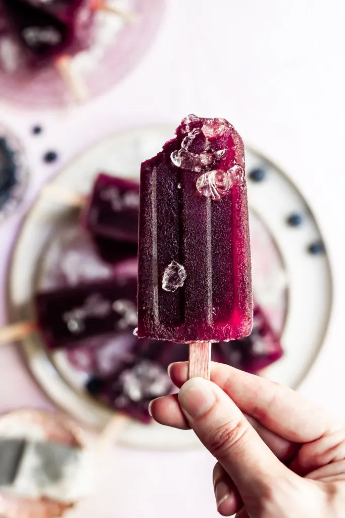 a bite taken from purple popsicle garnished with a few small pieces of ice