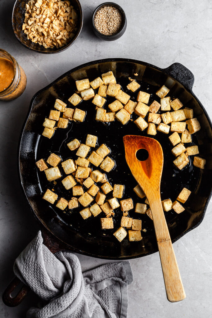 A cast iron skillet filled with crispy fried tofu cubes