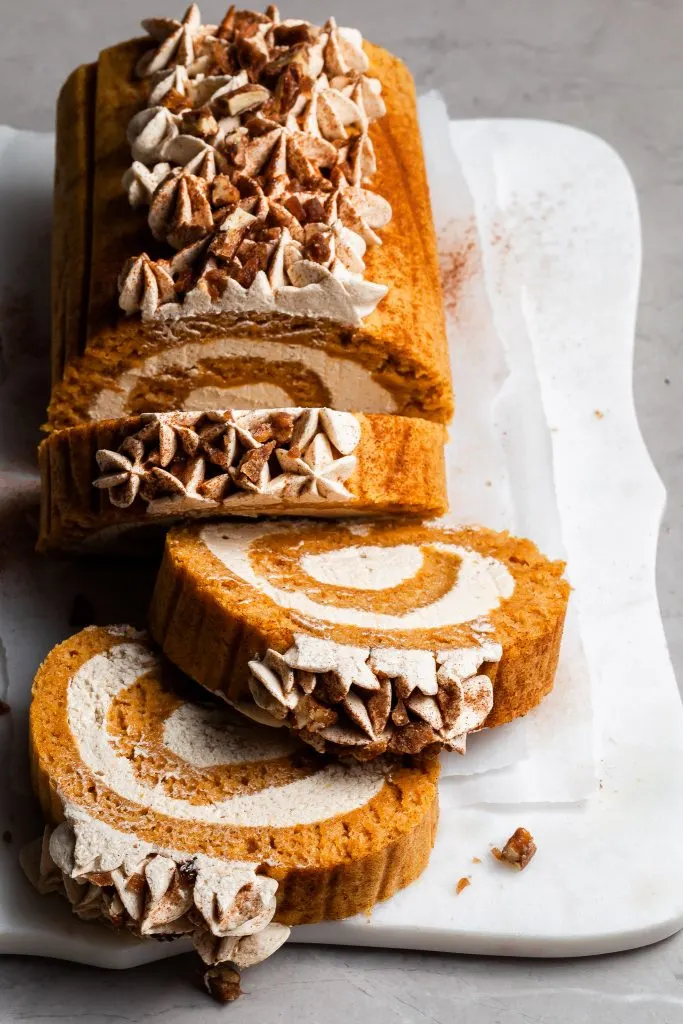 3 slices cut from a pumpkin cake roll resting on a white marble serving platter
