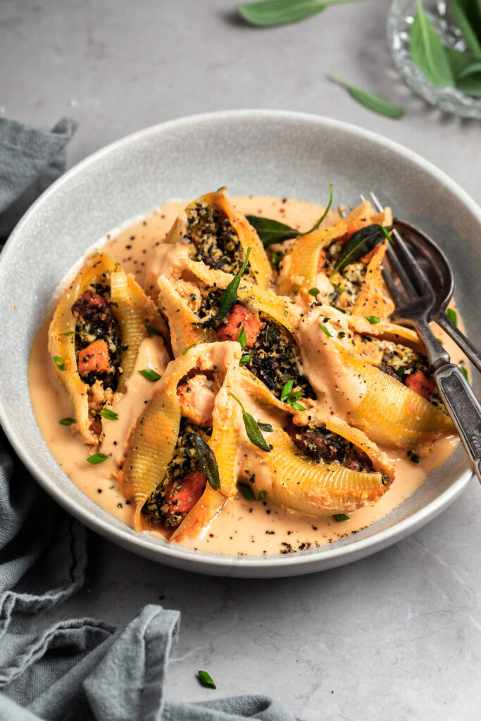 Bowl of stuffed pasta shells garnished with fried sage leaves
