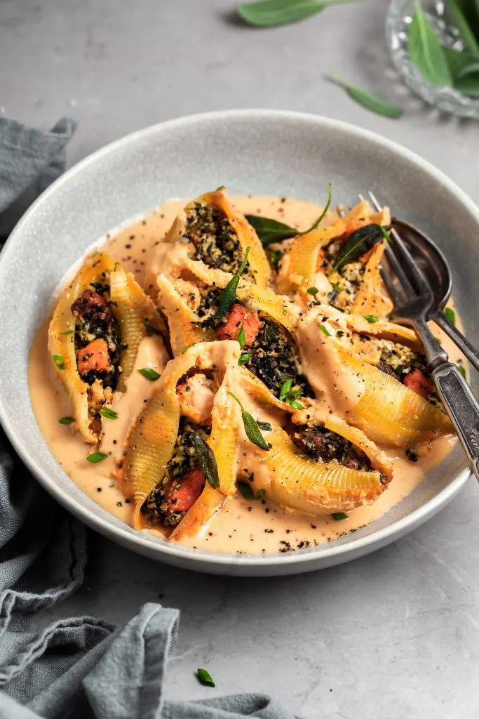 Bowl of stuffed pasta shells garnished with fried sage leaves
