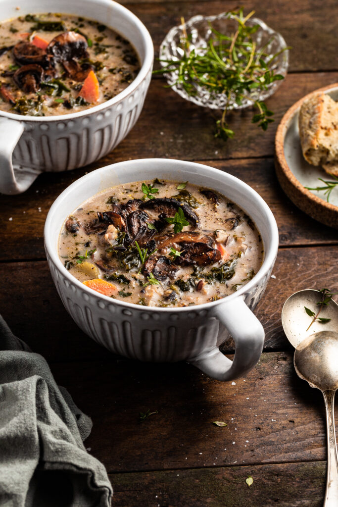 Large cup of mushroom soup beside a plate of crusty bread
