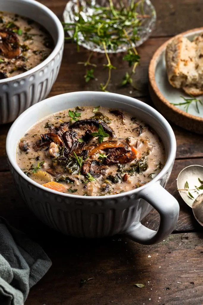 Close up of a bowl of vegan mushroom wild rice soup topped with herbs and  fried mushrooms