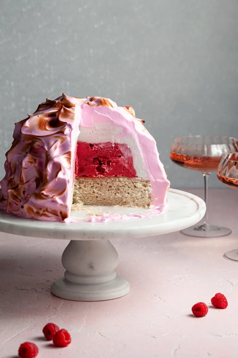 Pink meringue on a dome of ice cream cut with a slice missing. The center is white and dark pink