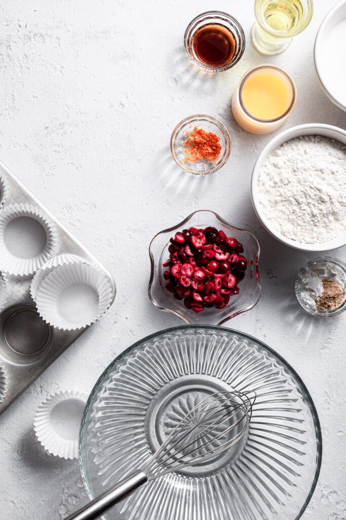 View looking down on a white counter where small bowls hold the ingredients for cranberry orange cupcake bases.