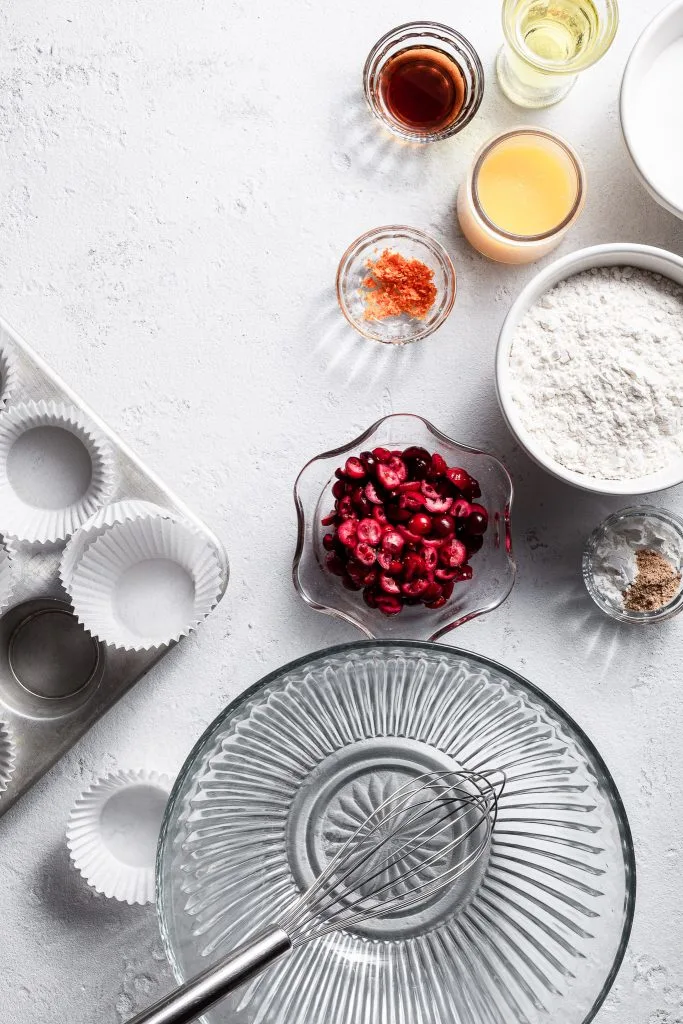 View looking down on a white counter where small bowls hold the ingredients for cranberry orange cupcake bases.