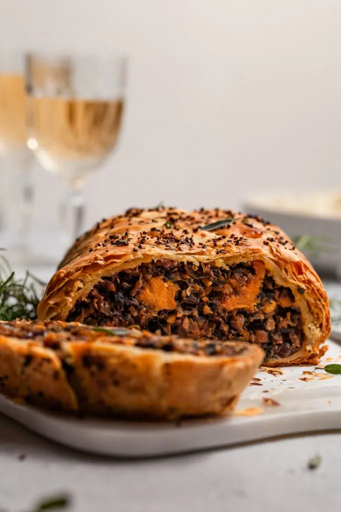 Close Up View of the inside of a sliced vegan wellington on a white marble serving platter