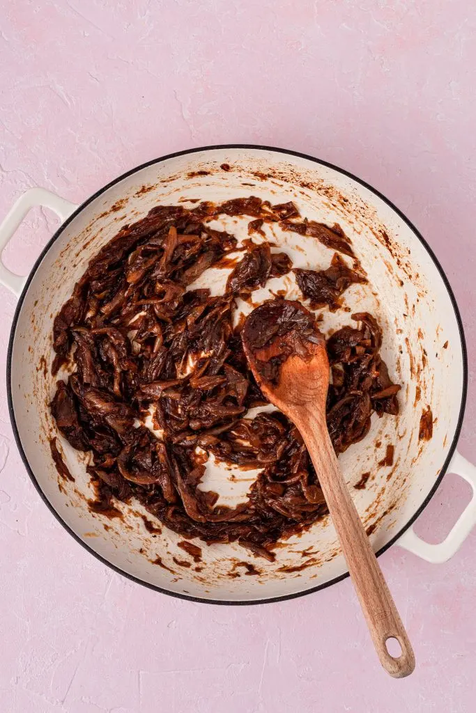 A white enamel skillet filled with caramelized onions.