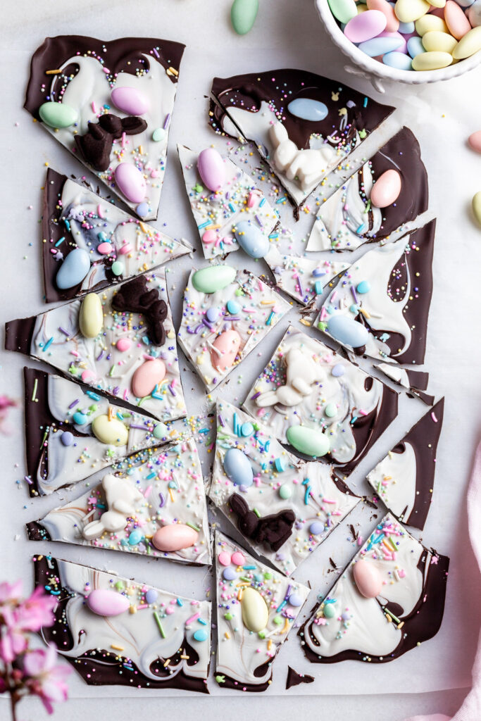 Easter bark broken into pieces on a piece of parchment paper beside a vase of spring blossoms