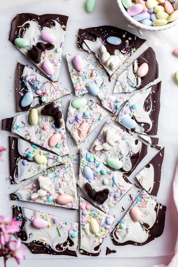 Easter bark broken into pieces on a piece of parchment paper beside a vase of spring blossoms