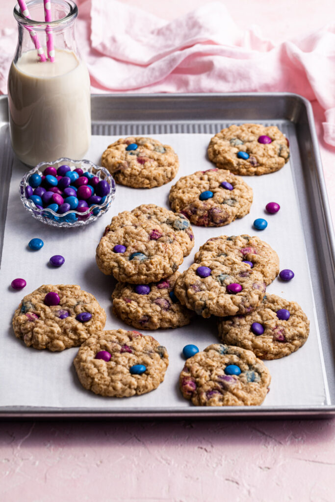 Cookies on a baking sheet with a bottle of milk and a small glass bowl of candies.