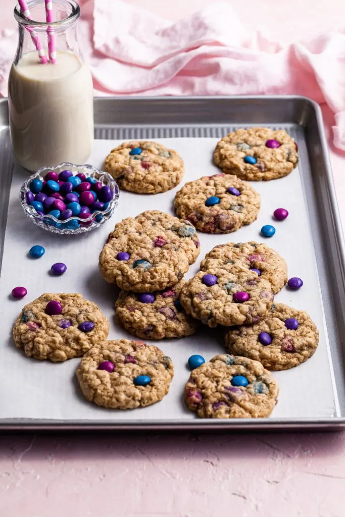 Cookies on a baking sheet with a bottle of milk and a small glass bowl of candies.