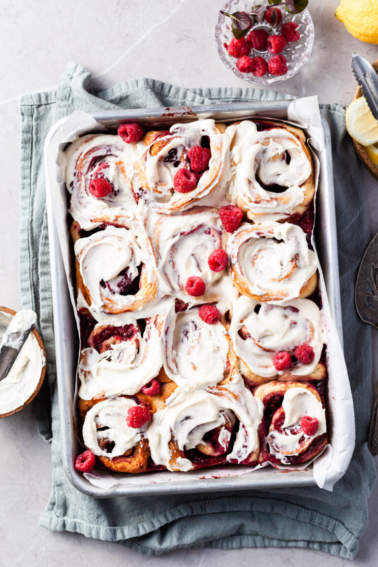 Aluminium baking pan filled with rapsberry sweet rolls covered in vanilla glaze