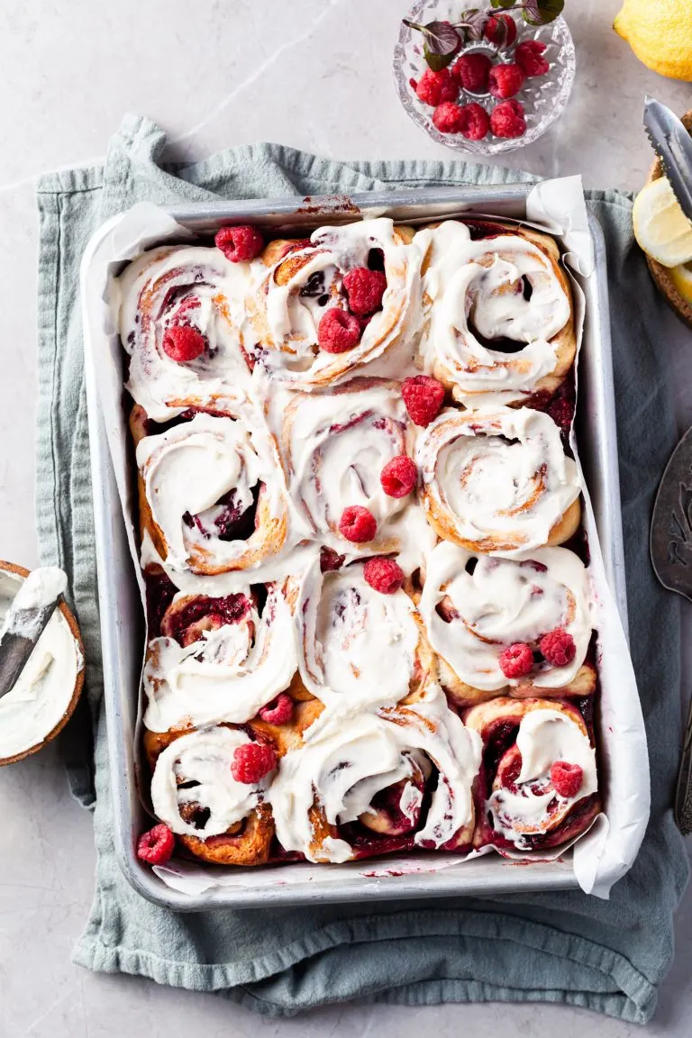Aluminium baking pan filled with rapsberry sweet rolls covered in vanilla glaze