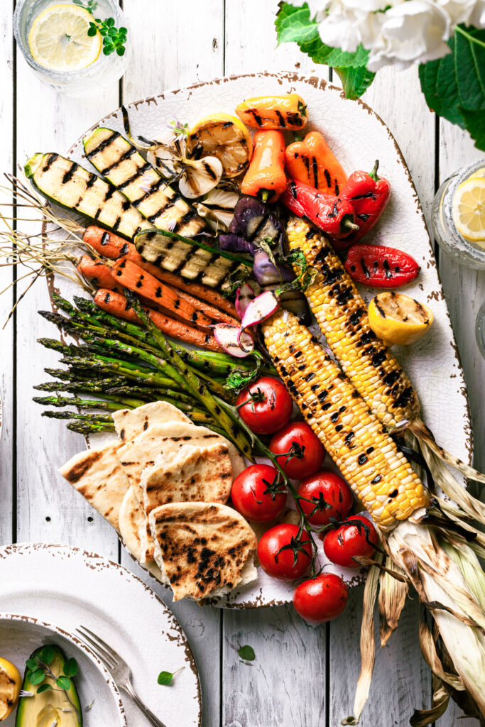 A platter of grilled vegetables on a white picnic table. 