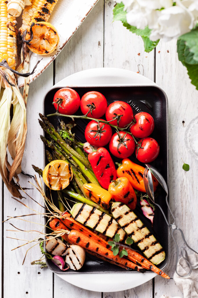 A white enameled cast iron grill covered in grilled vegetables. 