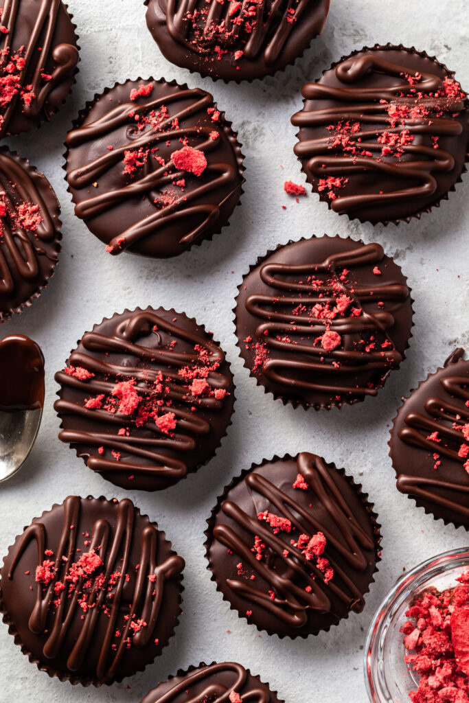 PB & J chocolates being drizzled with chocolate and sprinkled with crushed freeze dried strawberries