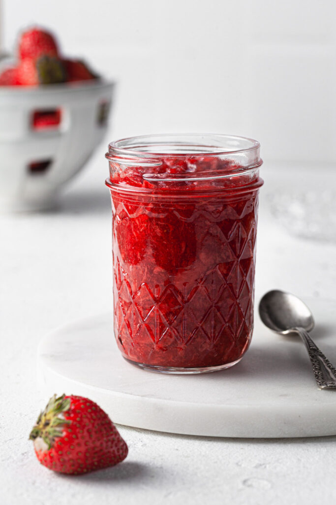 A glass jar filled with freshly made strawberry jam