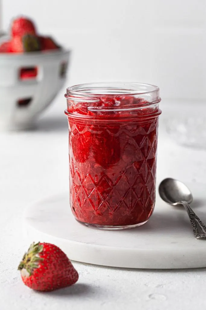 A glass jar filled with freshly made strawberry jam