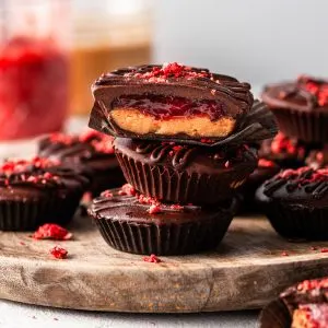 A stack of peanut butter and jam chocolate cups on a round wooden board