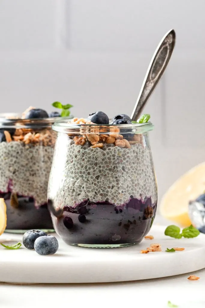Close up image of a small jar filled with chia pudding and blueberries