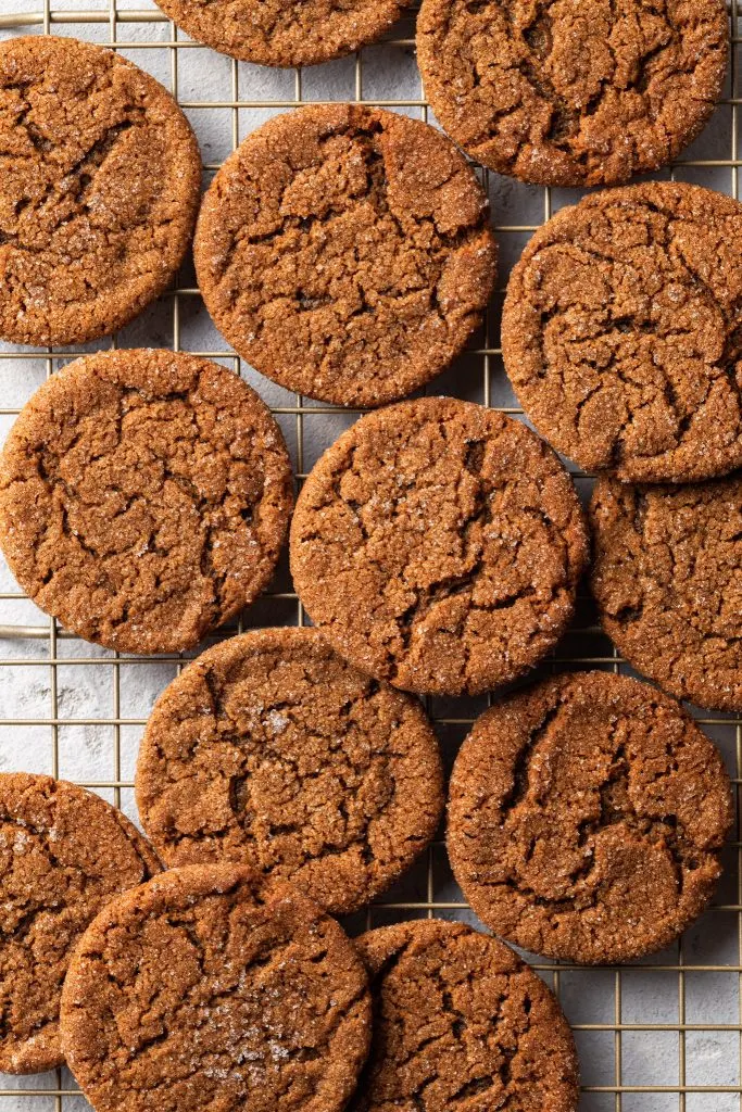 Vegan molasses cookies cooling on a gold cooking rack