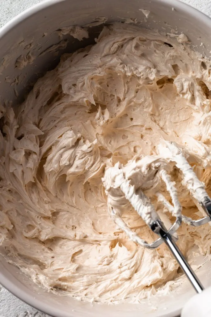 A white bowl filled with eggnog flavored whipped ermine frosting