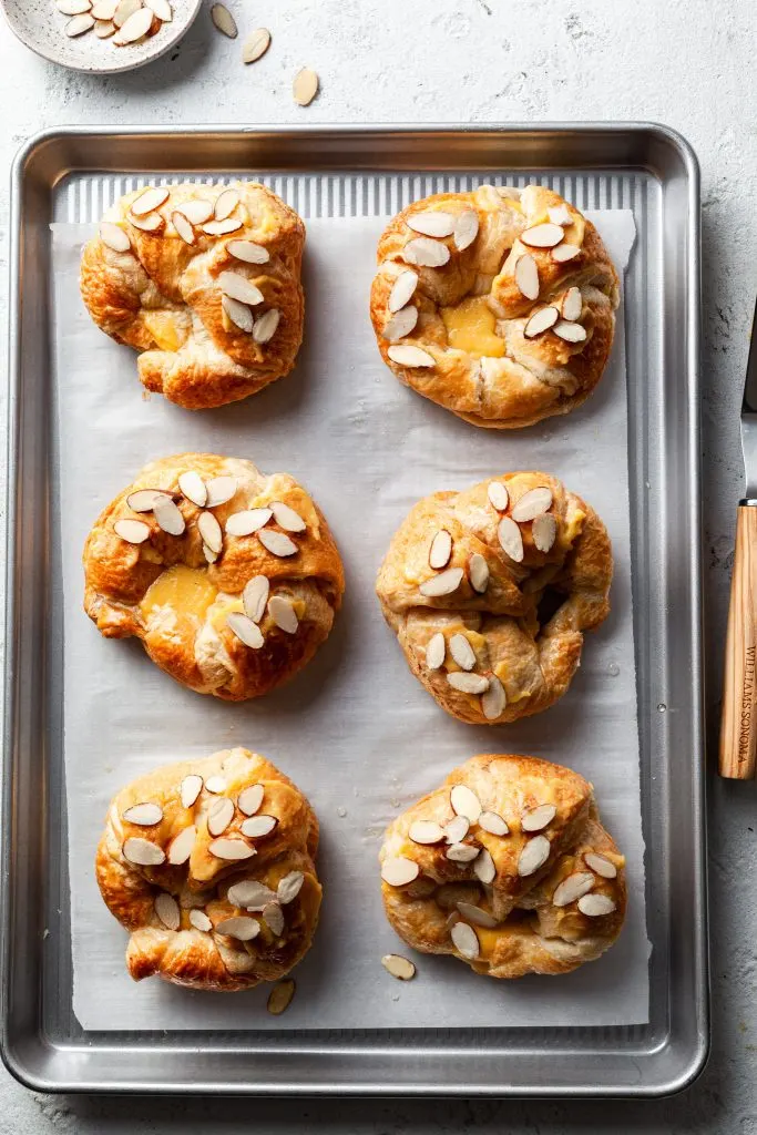 A baking sheet filled with 6 assembled vegan almond croissants.