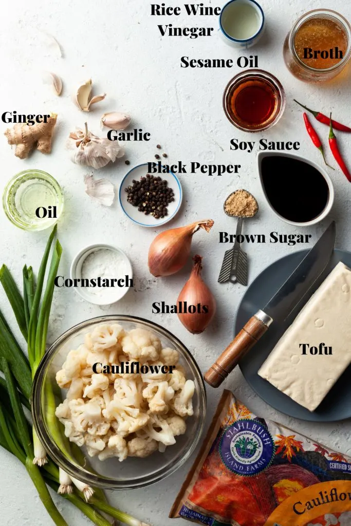 Premeasured and labeled ingredients for black pepper tofu and cauliflower laid out on a counter. 