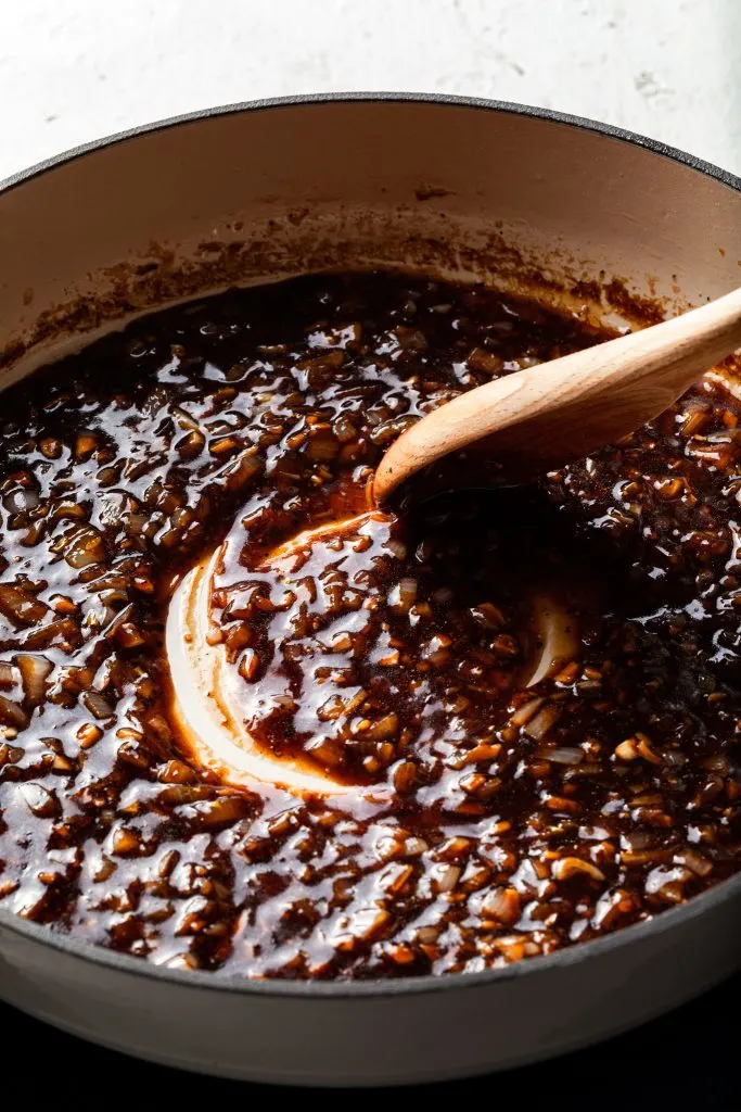 A white enamel skillet filled with an brown sauce. 