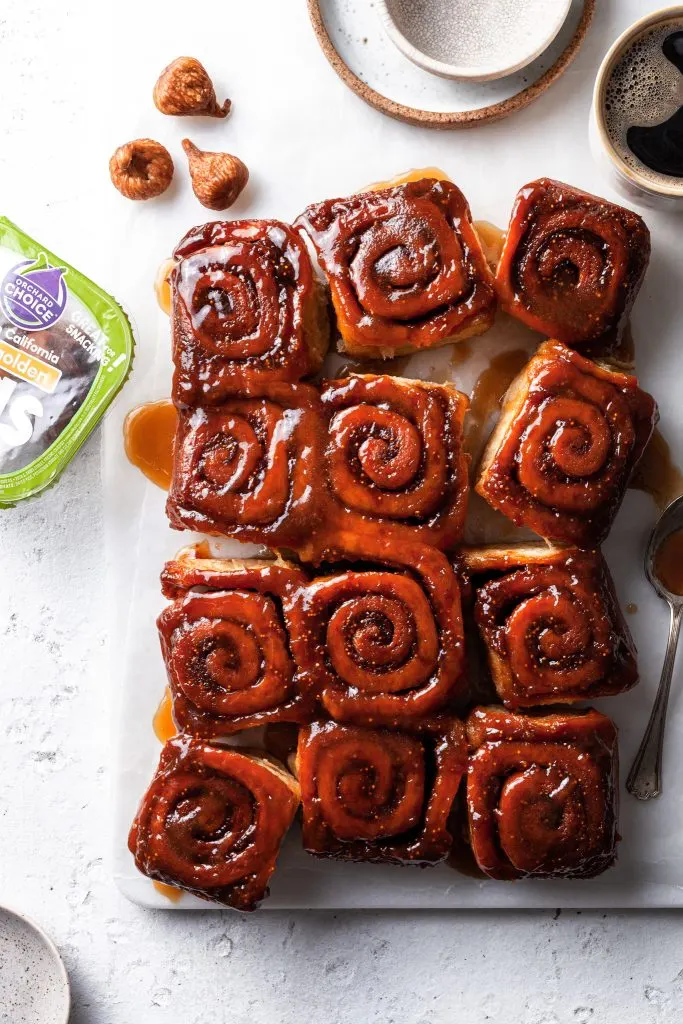 View looking down at a dozen sticky buns just broken apart to be served, along side a cup of coffee.