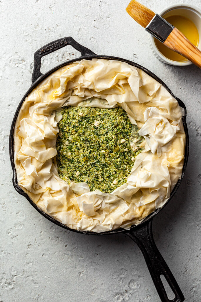 Assembled spanakopita in a cast iron pan, ready to be baked. 
