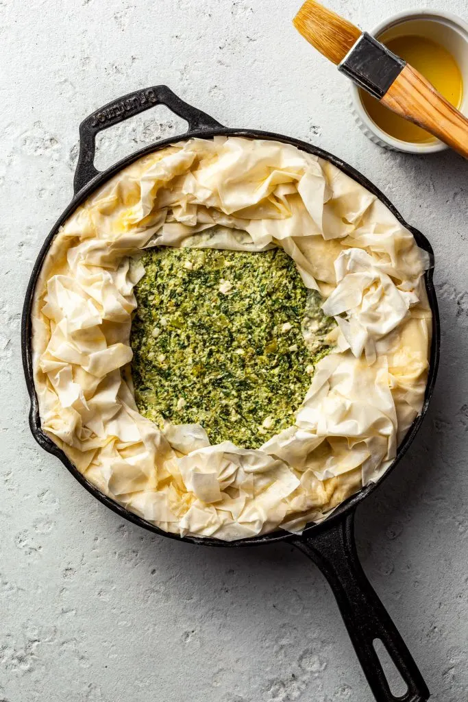 Assembled spanakopita in a cast iron pan, ready to be baked. 