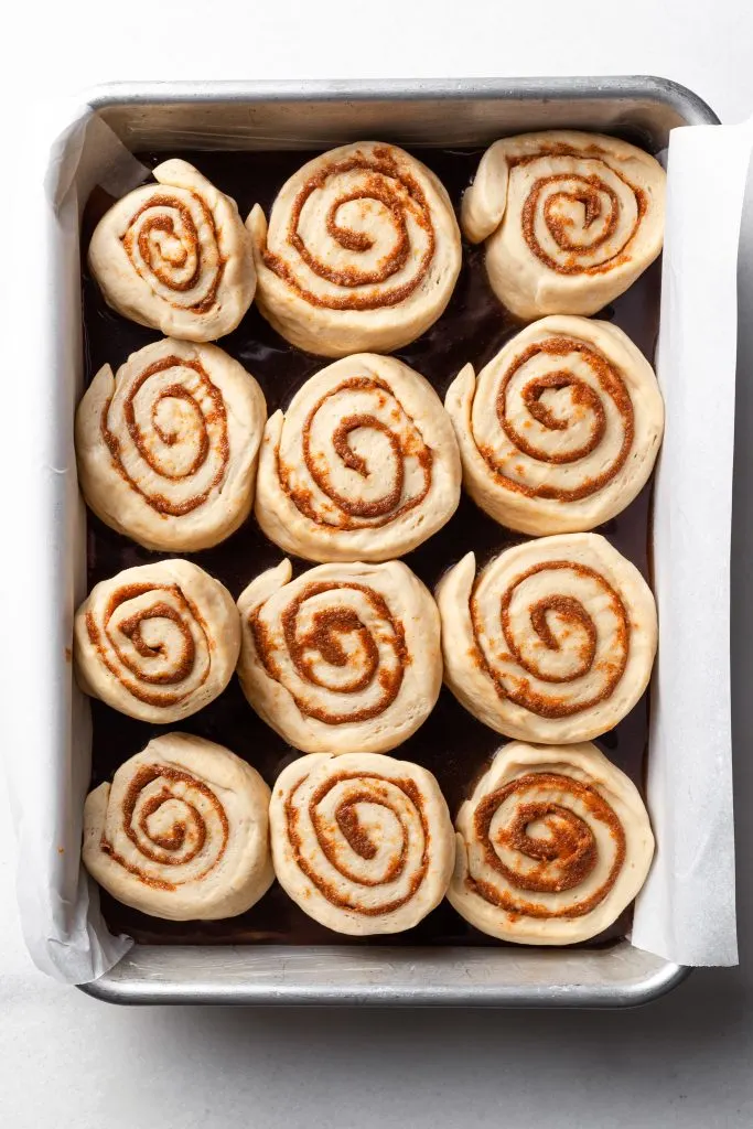 Fig rolls placed over caramel in a rectangular baking dish, unbaked. 