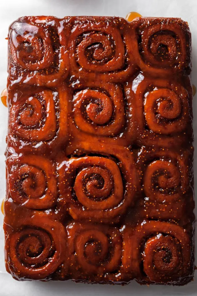 Sticky fig buns flipped over revealing their sticky glaze, and the small fig seeds in the spirals of the dough. 