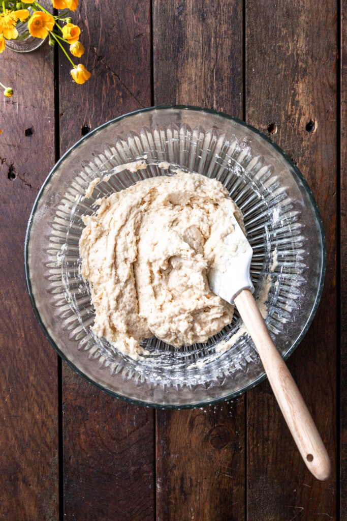 A glass bowl containing a lumpy drop biscuit batter. 
